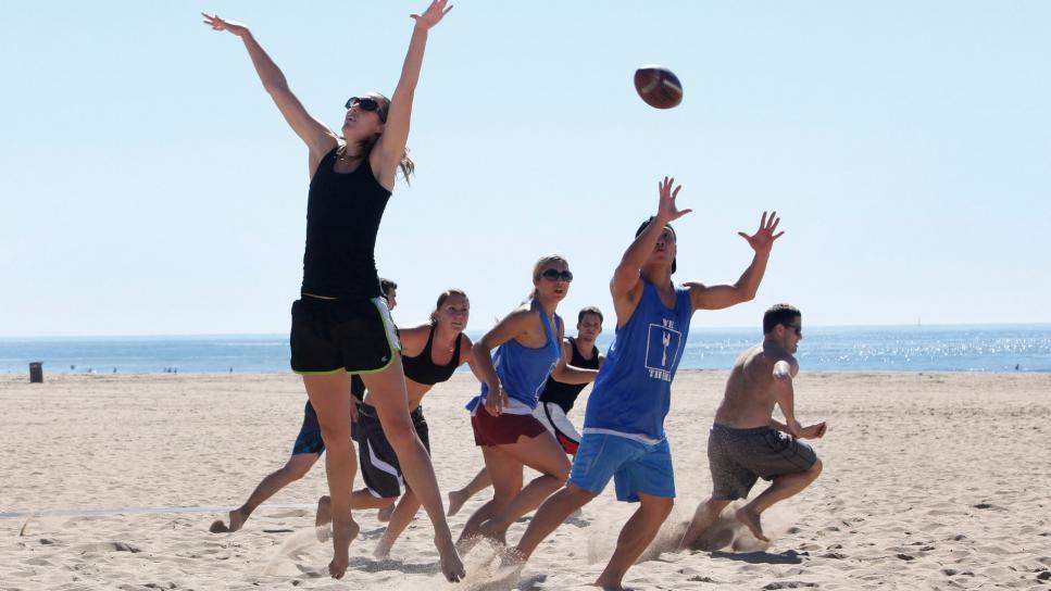 Megan Macdonald jumps to block a pass during a co-ed touch football game in Huntington Beach.