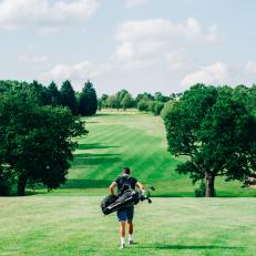 A golfer walking to the next shot on a bright day