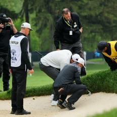 ROCHESTER, NEW YORK - MAY 20: Corey Conners of Canada, Scottie Scheffler of the United States and PGA Rules Official Mike Raby locate Conners' imbedded ball on the 16th hole during the third round of the 2023 PGA Championship at Oak Hill Country Club on May 20, 2023 in Rochester, New York. (Photo by Michael Reaves/Getty Images)