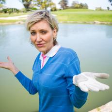 Confused female golfer looking at lake on a sunny day at the golf course