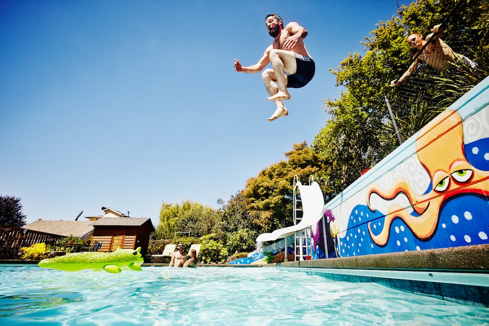 Man jumping from wall into outdoor pool