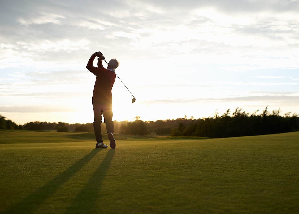 Senior golfer teeing off on golf course.