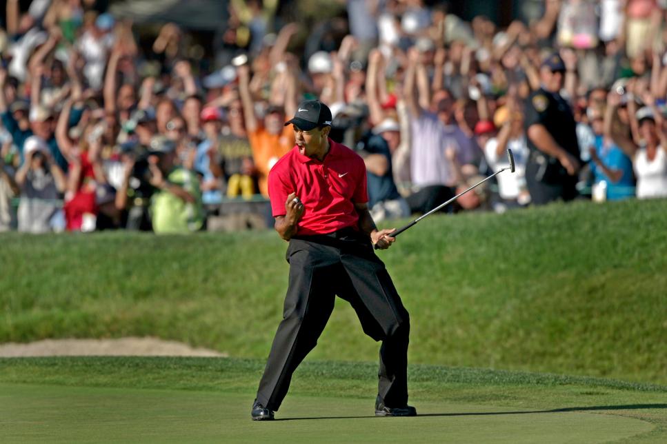 Tiger Woods celebrates on the eighteenth green after sinking a putt for a birdie and to force a pla
