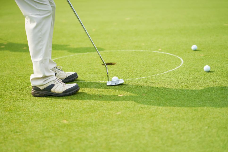 unrecognizable man playing golf on putting green in summer