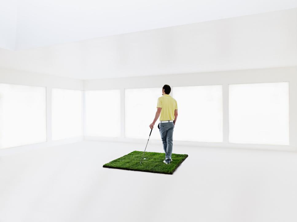 Male golfer holding club on grass in home
