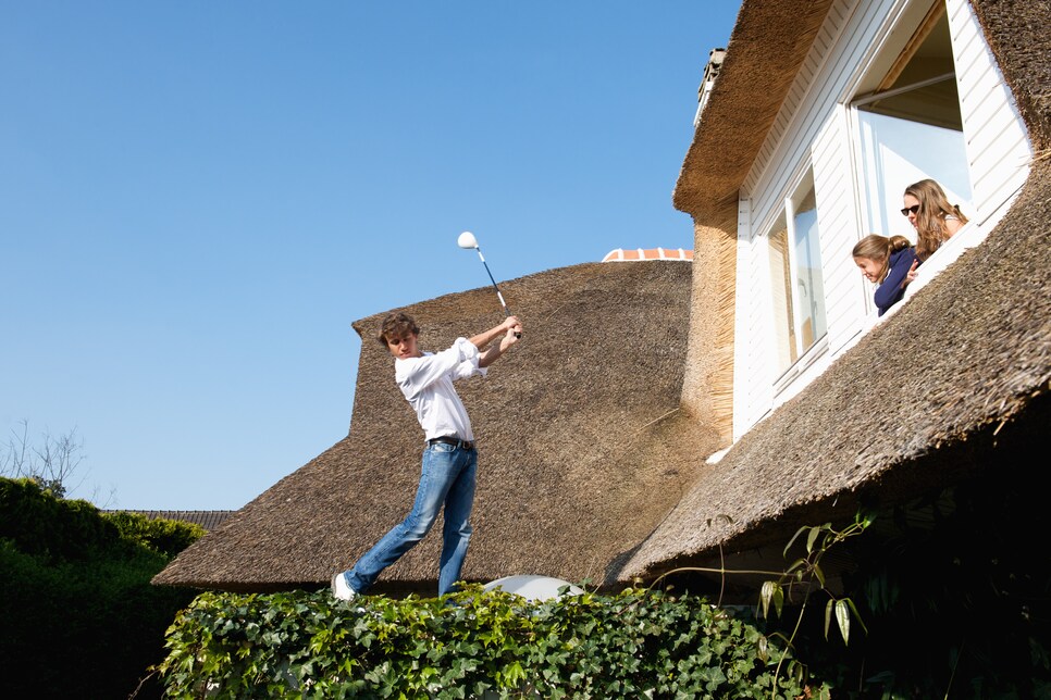 Girls watching boy play golf on roof