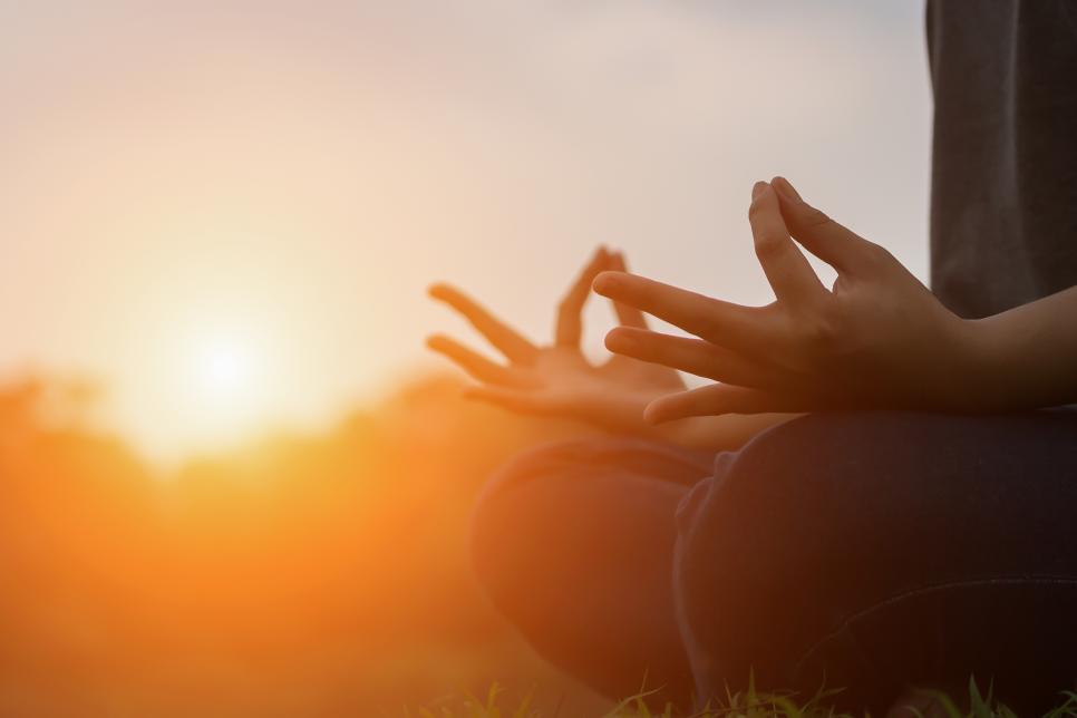 Close up of young woman doing yoga in the park with sunset