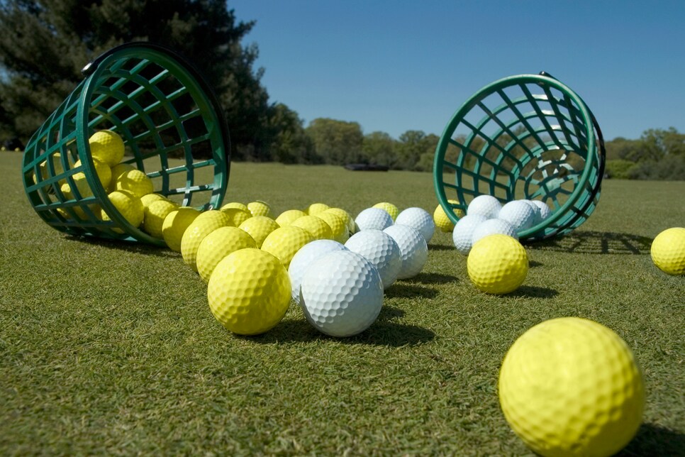 Two buckets of balls tipped over on grass