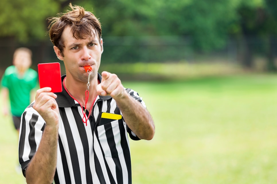 Soccer referee points and holds up red card