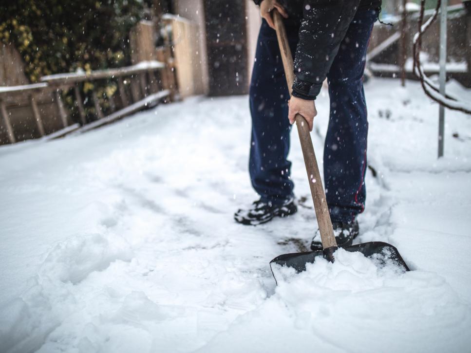 Senior man removing snow from his back yard