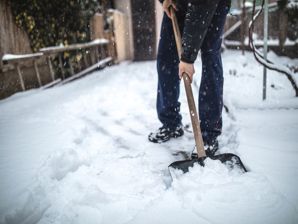 Senior man removing snow from his back yard