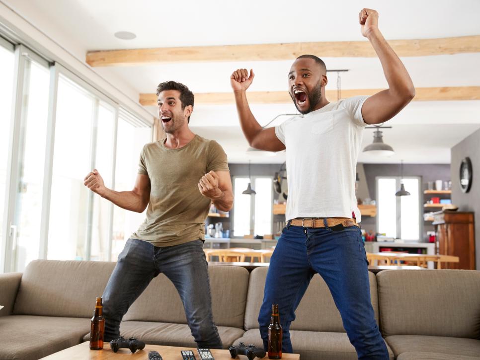 Two Excited Male Friends Celebrate Watching Sports On Television