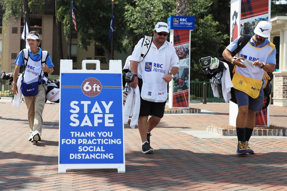 HILTON HEAD ISLAND, SOUTH CAROLINA - JUNE 19: Caddies walk past signage promoting social distancing as a COVID-19 precaution during the second round of the RBC Heritage on June 19, 2020 at Harbour Town Golf Links in Hilton Head Island, South Carolina. (Photo by Streeter Lecka/Getty Images)