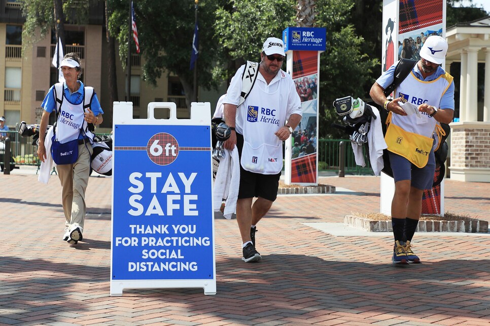 HILTON HEAD ISLAND, SOUTH CAROLINA - JUNE 19: Caddies walk past signage promoting social distancing as a COVID-19 precaution during the second round of the RBC Heritage on June 19, 2020 at Harbour Town Golf Links in Hilton Head Island, South Carolina. (Photo by Streeter Lecka/Getty Images)