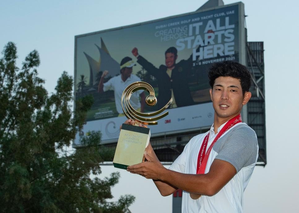 Keita Nakajima of Japan with the AAC trophy in front of a Hideki Matsuyama bill board on the 11th hole. The 2021 Asia-Pacific Amateur Championship is being played on the Dubai Creek Golf and Yacht Club, in Dubai, United Arab Emirates on Saturday, November 6, 2021. Photograph by AAC