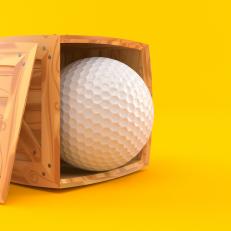 Golf ball inside cargo crate isolated on orange background. 3d illustration