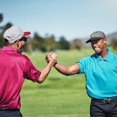 Shot of two cheerful young male golfers engaging in a handshake after a great shot on the golf course