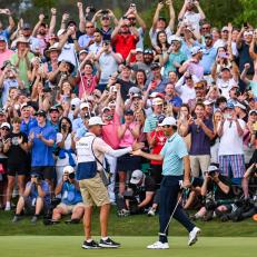 PONTE VEDRA BEACH, FLORIDA - MARCH 12:  Scottie Scheffler celebrates with his caddie Ted Scott after his five stroke victory on the 18th hole green with fans cheering behind during the final round of THE PLAYERS Championship on the Stadium Course at TPC Sawgrass on March 12, 2023 in Ponte Vedra Beach, Florida. (Photo by Keyur Khamar/PGA TOUR via Getty Images)