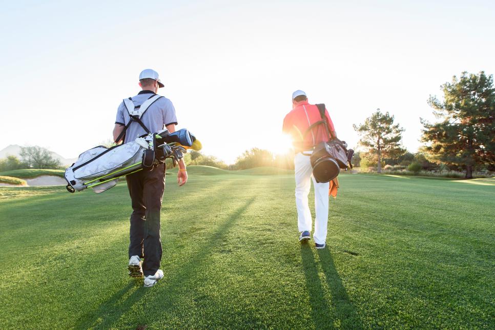 Men carrying golf bags on sunny golf course